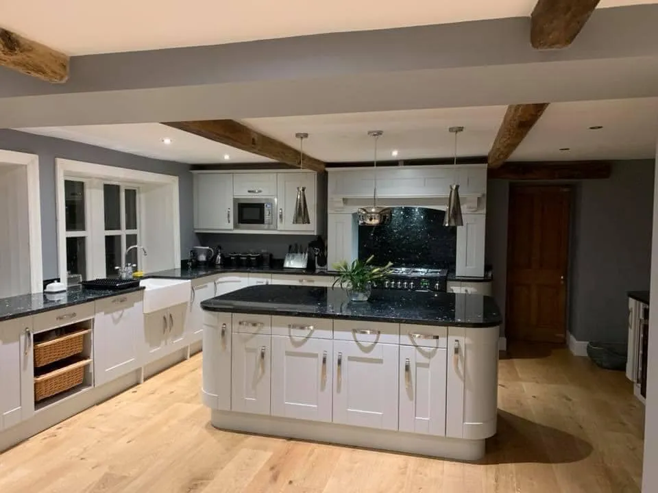 A kitchen with white cabinets and black counter tops.